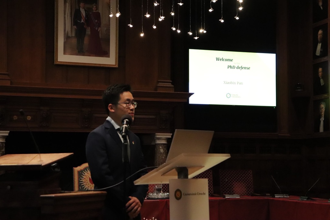 Xiaobin Pan speaking at the lectern at the beginning of his PhD defense